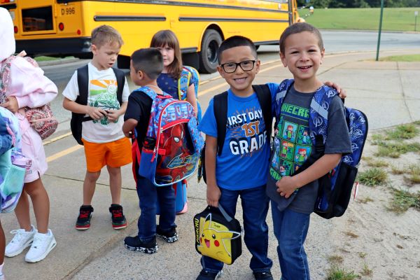 Children with backpacks near a school bus.